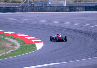 Red formula car driving on a left corner. Historical racing car