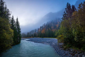 river in the karwendel mountains of austria in autumn at sunrise with fog 
