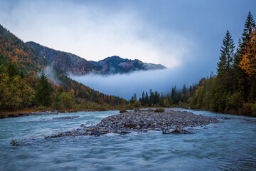 mountain river in the autumn at karwendel mountains in the alp of austria during sunrise with fog