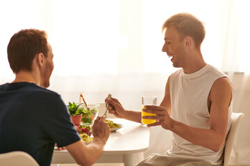 A happy couple eating tasty pasta together, enjoying each others company in a stylish kitchen.