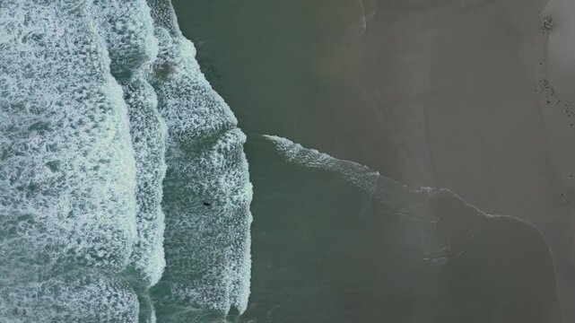 Drone shot of Foamy Sea Waves On Thesandy  Beach In Caion, A Laracha, Spain