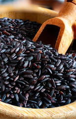 Wooden bowl overflowing with black rice on checkered cloth