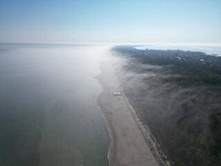 Aerial View of Coastline with Fog, Calm Sea, and Green Vegetation Creating Natural Textures