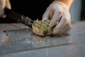 Chef slicing sushi roll with sharp knife