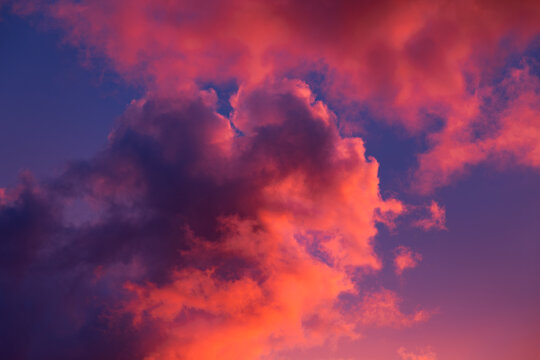 Amazing sunset with beautiful cumulus clouds coloured  pink, red, orange, purple by the sun. Dramatic celestial landscape.