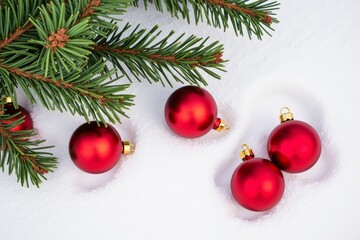 Festive christmas decorations with red ornaments and pine branch on snowy background