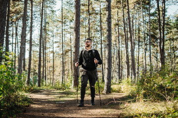 Young caucasian man hiking or trekking through the forest	