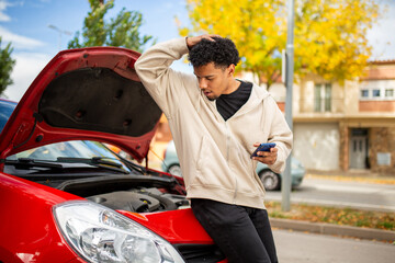 Naklejka premium Frustrated man with broken down car using phone for help