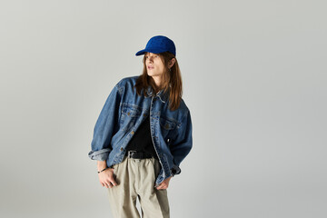 A stylish young man poses in trendy clothes and a cap against a plain backdrop.