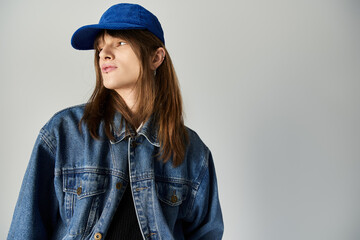 A young man dressed in stylish apparel confidently poses against a clean backdrop.