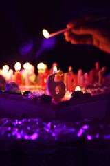 Festive birthday cake with lit candles and candles number '6' topper sits on a table in party. Lighting birthday Candles in night party with friend together. Birth day concept.