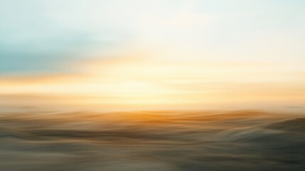 Blurry sunset with hues of gold and soft blue blending into sandy tones