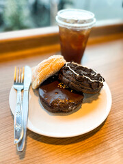 delicious donuts with different toppings served on white plate and cup of coffee