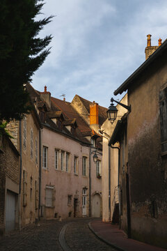 View of charming cobblestone street with stone buildings and street lamp in evening light, Beaune, France.