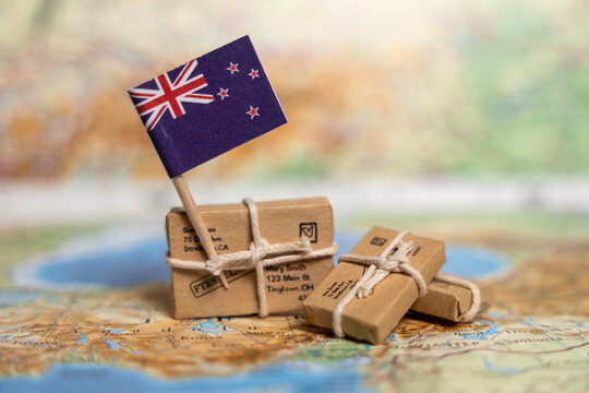 New Zealand International Shipping and Delivery: Small Packages with New Zealand Flag on World Map - Global Postal Service and Worldwide Logistics - Powered by Adobe