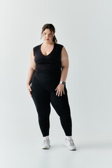 Obraz premium A beautiful plus size woman poses gracefully in fitted black attire, showcasing her elegance.