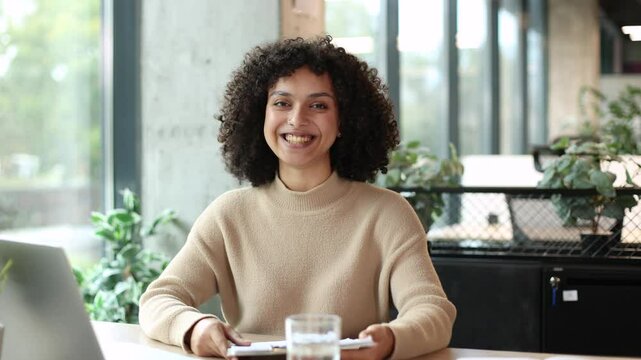 Happy beautiful businesswoman blogger looking talking to camera. Pretty girl recording vlog at office, smiling lady speaking to camera and making video conference call online.