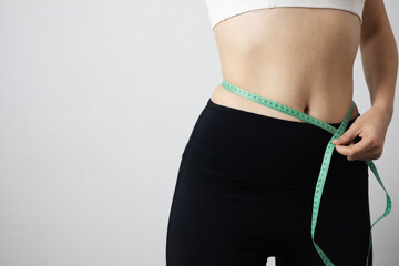 Measuring a woman's waist with a tape measure, focusing on body positivity and healthy weight management.