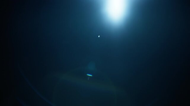 Abstract blue lens flare on black background. Slow motion. 