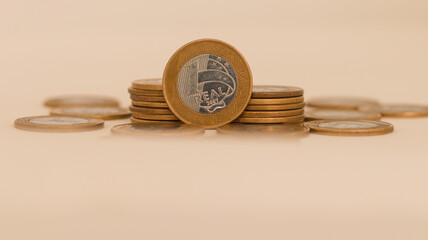 Poupança de moedas amontoadas de um real brasileiro, simbolizando finanças pessoais e economia