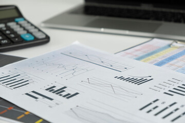 A modern office desk with a laptop financial reports