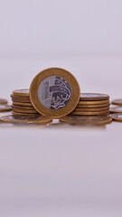 Uma moeda de um real em foco, com outras moedas de um real ao fundo, representando o valor monetário do Brasil, em um cenário simples e clean, com iluminação suave.
