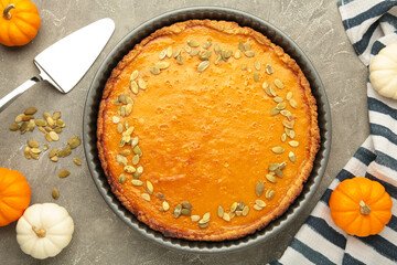 Delicious pumpkin pie with mini pumpkins on grey concrete background. Thanksgiving day. Top view