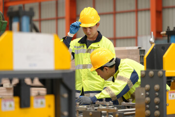 two professional engineer, worker, technician use clipboard discuss work, walk in steel metal manufacture factory plant industry. Asian man and woman wear hard hat check quality machine