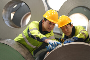 two professional engineer,worker,technician use clipboard discuss work, walk in steel metal manufacture factory plant industry. Black African American man and woman wear hard hat check quality machine