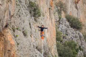 A tightrope walker walks along a cable stretched over a canyon.