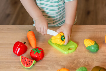 toddler baby boy child having fun playing alone with cooking toys in living room at home
