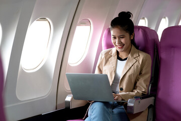young businesswoman uses laptop while flying airplane for work