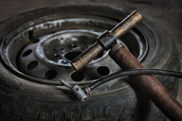 Old vintage car air pump close-up on a flat tire background