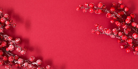 Christmas composition. Red berries on a branch in frost on a dark red background. Winter or Christmas background. Flat lay. banner