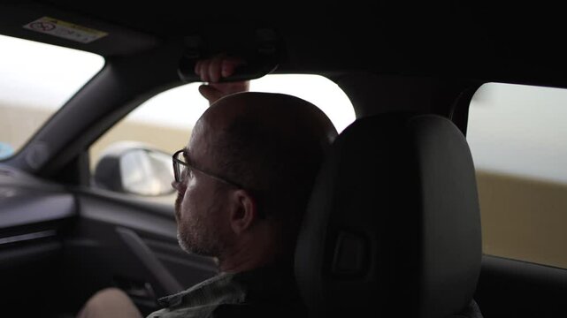 horizontal video of co-driver in fear of driving, holding on to the handlebars of the car. man in his forties, with glasses and bald head.