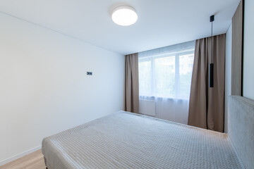 Wide Angle of Home Bedroom Interiom. King Size Double Bed and Windows in Background. White Walls. Family Home. Long Curtains.
