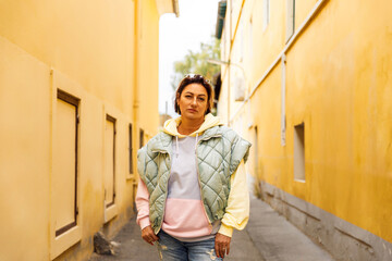 Casual woman in urban alleyway surrounded by yellow architecture