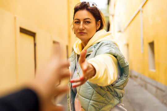 Woman reaching out with hand in yellow alleyway