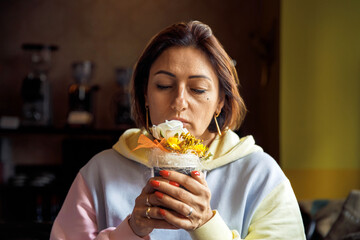 Woman enjoying a fragrant flower arrangement in a cozy indoor setting