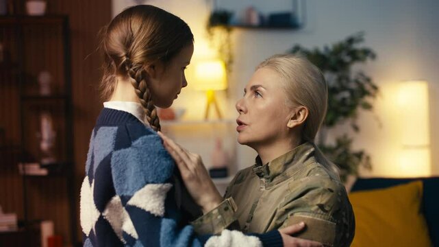 Caring soldier mom leaving for the military kisses and hugs her little daughter