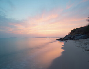 beach at sunrise with calm waters reflecting the pastel colors of the sky