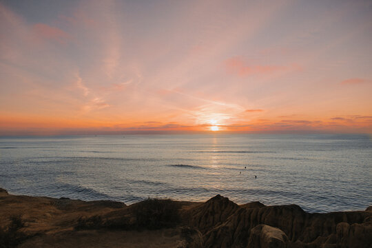sunset over the ocean, sunset cliffs sunset, pink skies, surfers in the water,  sunset at the beach, beach sunset, San Diego sunset, 