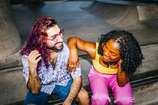 High angle view of curly hair woman with hand on shoulder of male friend sitting under bridge