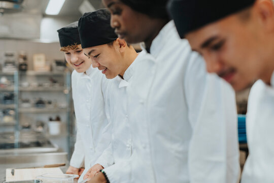 Smiling male and female trainee chefs practicing in culinary school