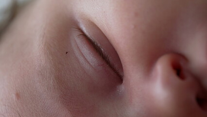 Close-up of baby’s closed eyes and gentle eyelashes, tear drop near eye, capturing peaceful sleep...