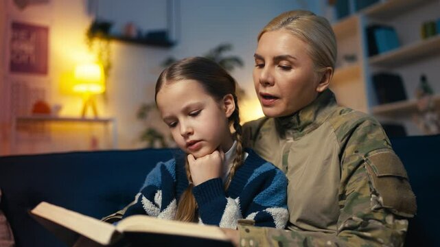 Service member mother and her little daughter reading together, upbringing