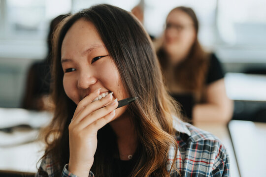 Happy female student with hand covering mouth at school