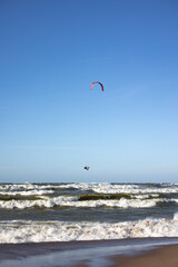 Kitesurfer Soaring Above the Waves on a Sunny Day at the Beach with Clear Blue Sky
