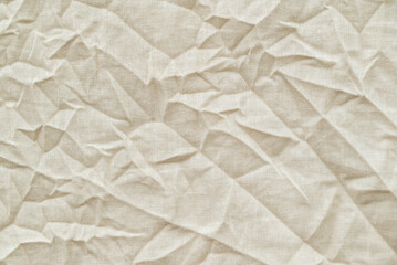 Close up shot of crumpled fabric. Beige natural cotton fabric with many wrinkles, texture background