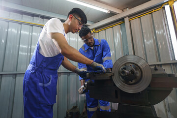 Diversity mechanic worker or metalworker using metal lathe machine operate polishing car disc brake at auto repair garage. Maintenance automotive and inspecting vehicle part concept
